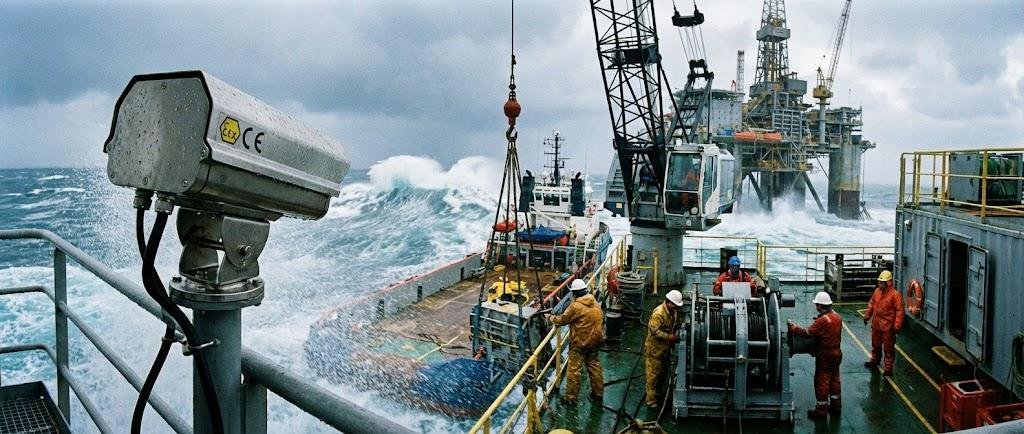 SWGJ explosion-proof camera (customized 316L stainless steel) monitoring an offshore marine platform and oil rig deck in stormy seas.