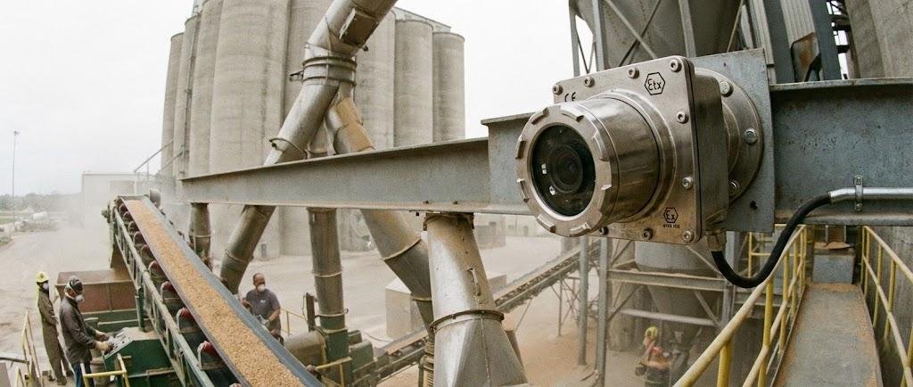 SWGJ stainless steel explosion-proof camera monitoring grain conveyor belts and silos in a dusty agricultural processing facility.